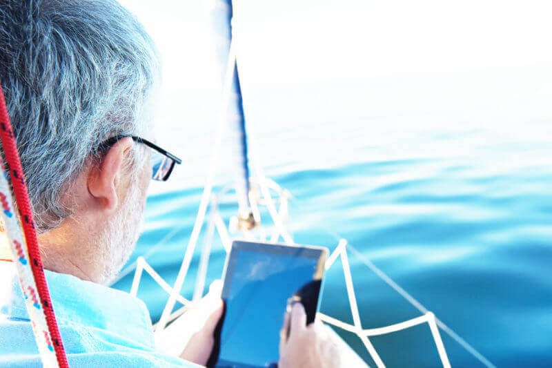 man looking at a tablet computer on a yacht