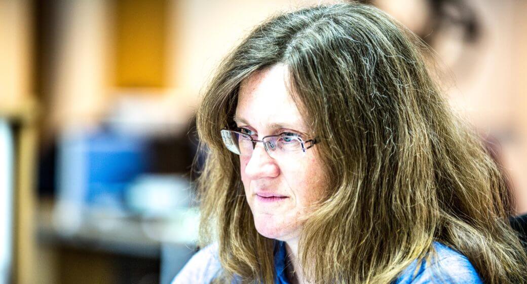 woman in glasses looking at a computer screen