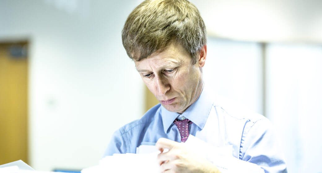 man looking at books in an office with a tie