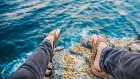 Tax when working abroad flip flops and feet on cliff