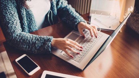 Close up on the hands of young woman using computer, tablet and smart phone - business, technology, multitasking concept