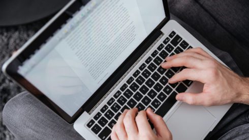 Close up portrait of a man typing on laptop while sitting on sofa sussex accountants